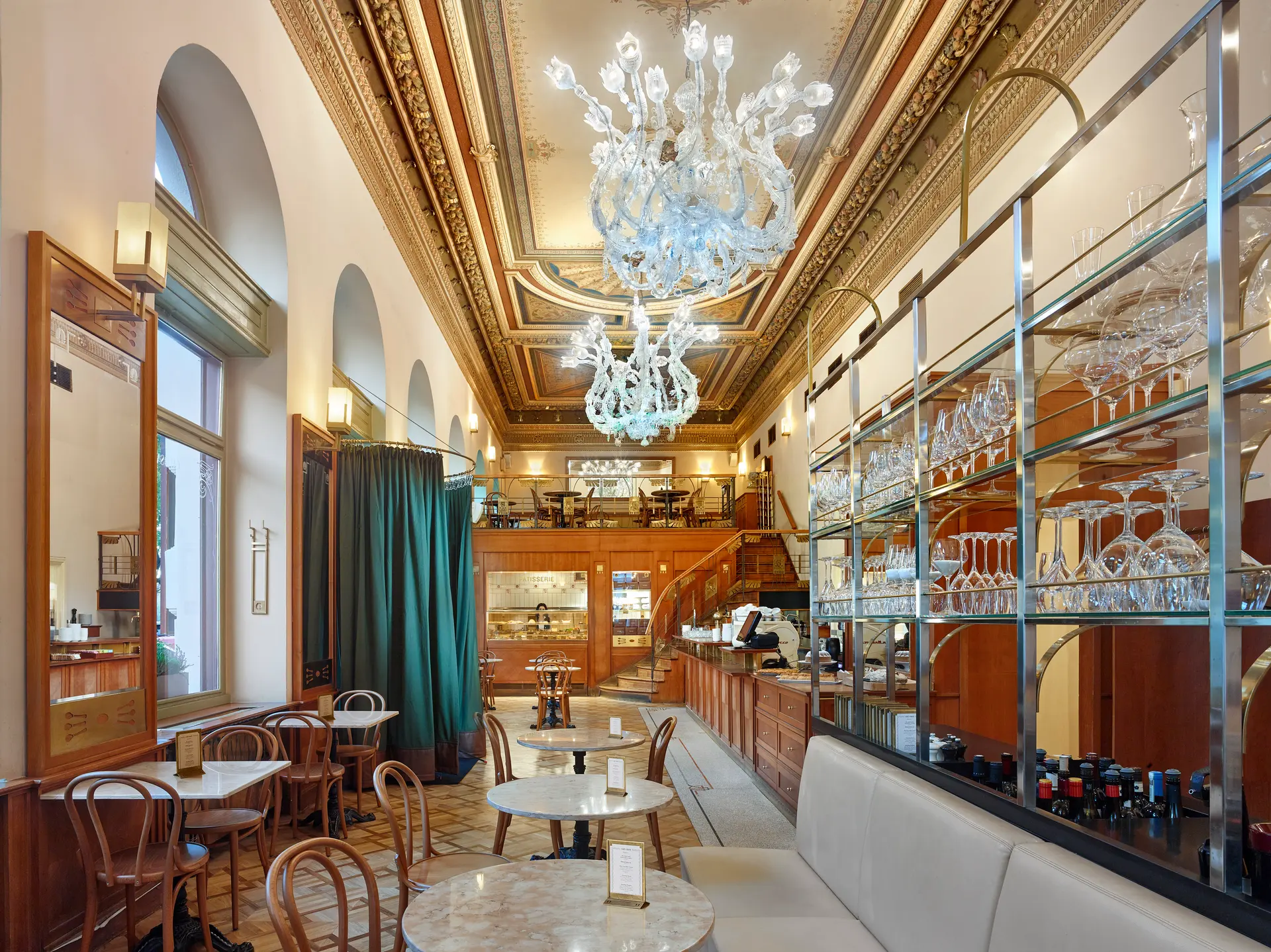 Interiér kavárny a restaurace Café Savoy s lustry a galerií.