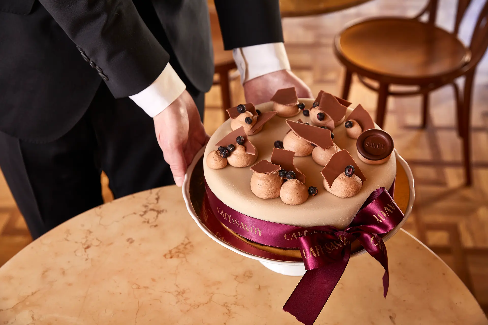 Waiter serving a chocolate cake from Café Savoy on a table in the café.